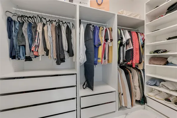 a view of walk in closet with clothes and shoes