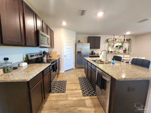 a kitchen with stainless steel appliances granite countertop a sink stove and refrigerator