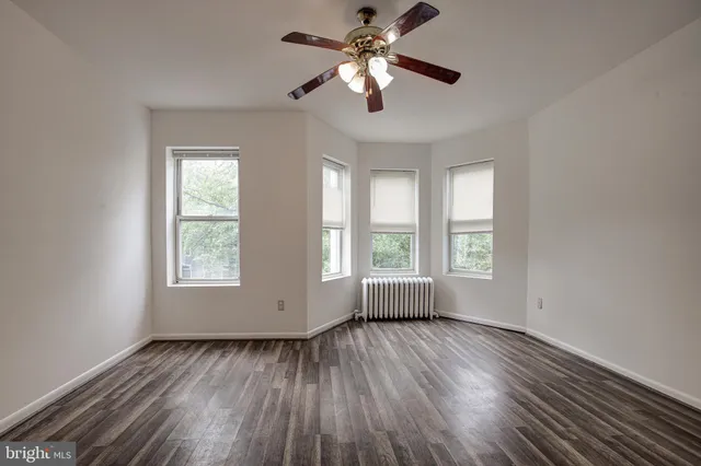 a view of empty room with wooden floor and fan