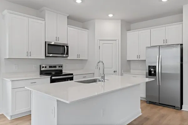 a kitchen with stainless steel appliances a stove a sink a refrigerator a microwave and cabinets