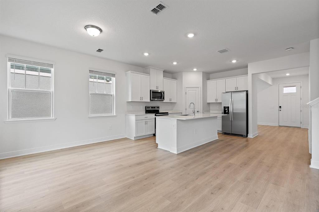 2276 Hen Road Minneola, FL 34715 - Photo 12 of 40 a view of kitchen with kitchen island stainless steel appliances refrigerator oven sink and white cabinets with wooden floor