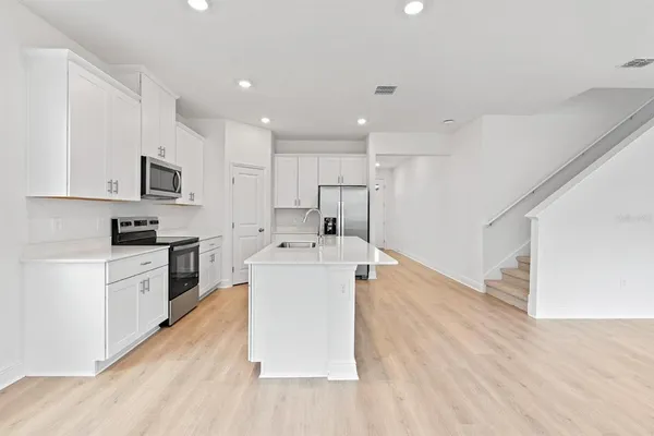 a kitchen with a sink a stove top oven and white cabinets