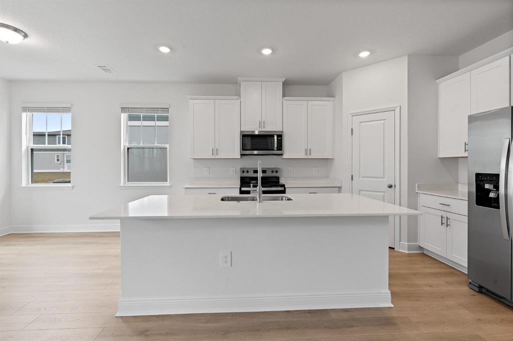2276 Hen Road Minneola, FL 34715 - Photo 7 of 40 a kitchen with kitchen island white cabinets and refrigerator