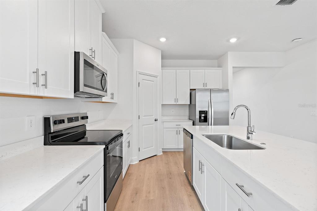 2276 Hen Road Minneola, FL 34715 - Photo 8 of 40 a kitchen with white cabinets and white appliances