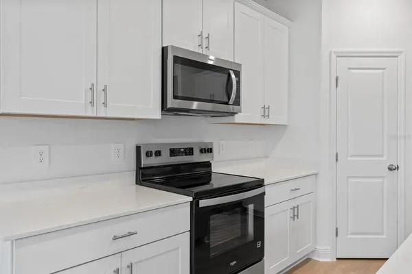 a kitchen with stainless steel appliances granite countertop white cabinets and a stove a oven with white countertops
