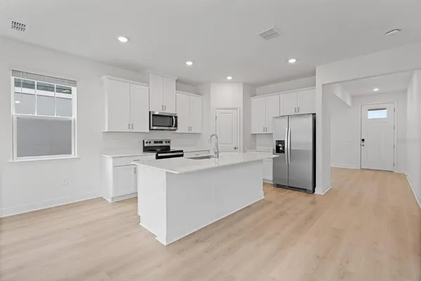 a kitchen with stainless steel appliances white cabinets and wooden floor