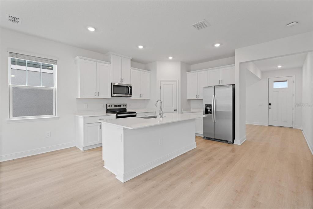 2276 Hen Road Minneola, FL 34715 - Photo 10 of 40 a kitchen with stainless steel appliances white cabinets and wooden floor