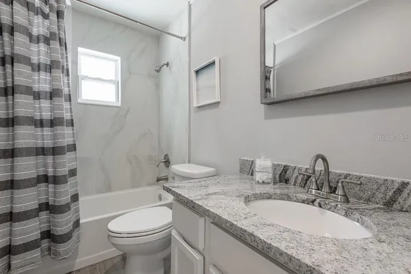 a bathroom with a granite countertop double vanity sink toilet and shower