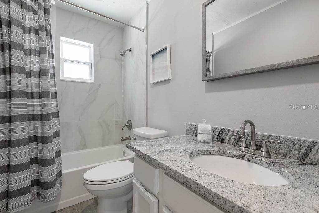 15732 Bolesta Road, Unit A Clearwater, FL 33760 - Photo 11 of 13 a bathroom with a granite countertop double vanity sink toilet and shower
