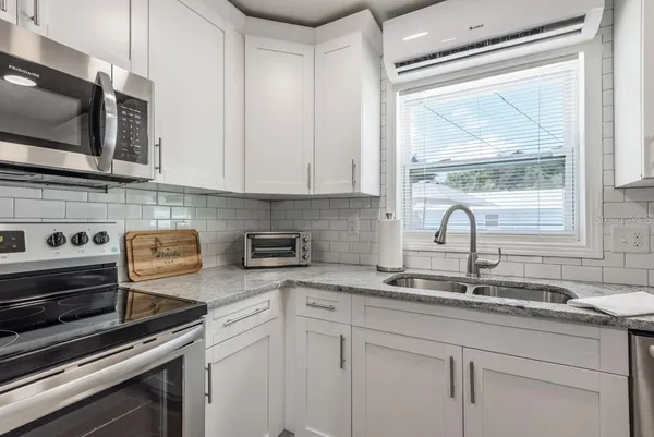 a kitchen with stainless steel appliances white cabinets a sink and a stove