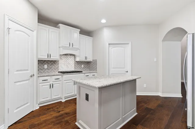 a kitchen with stainless steel appliances granite countertop a stove a sink and white cabinets