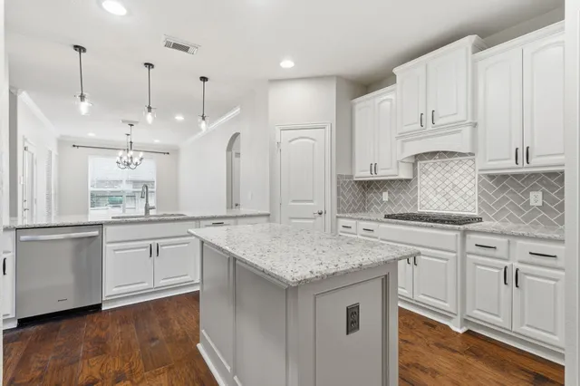 a kitchen with kitchen island granite countertop a sink cabinets and wooden floor