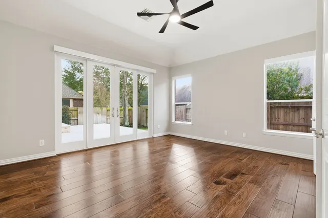 a view of an empty room with wooden floor and a window