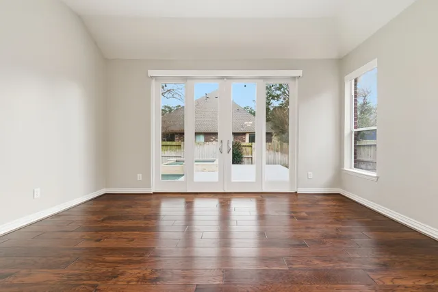 a view of an empty room with wooden floor and a window