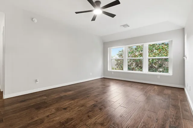 an empty room with wooden floor and windows
