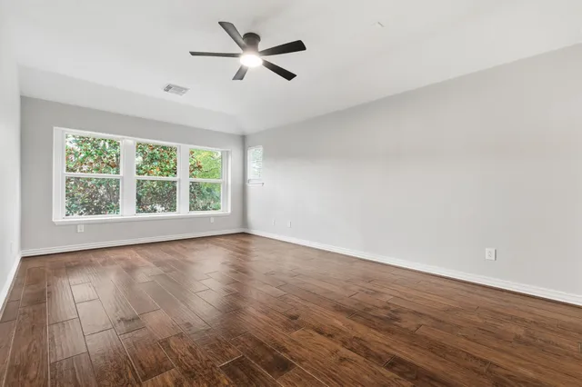 an empty room with wooden floor and ceiling fan