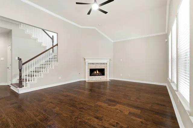 a view of an empty room with wooden floor fireplace and a window