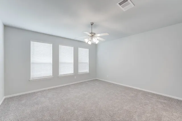 an empty room with a chandelier fan and windows