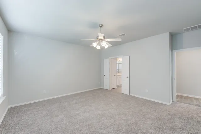 a view of an empty room with a chandelier fan
