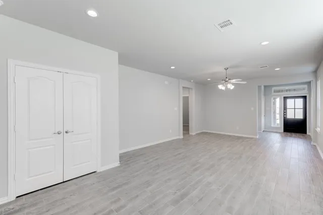 an empty room with wooden floor and windows