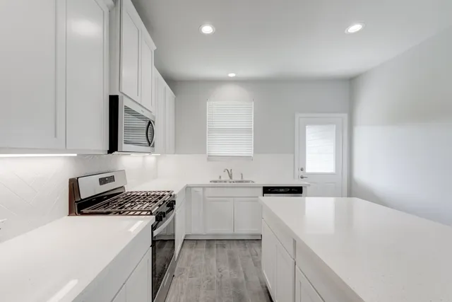 a kitchen with granite countertop a sink stove and cabinets
