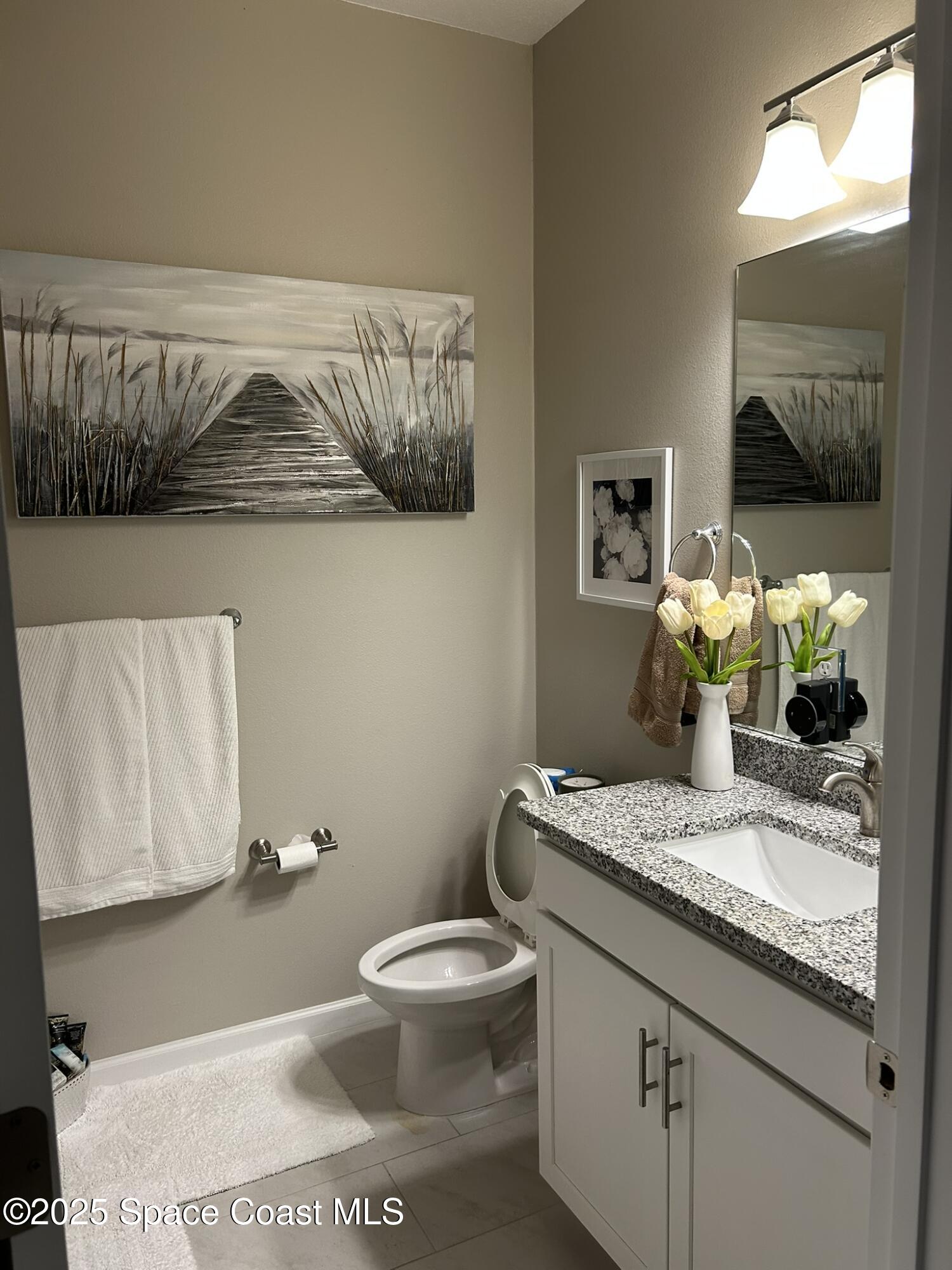 3931 Playa Del Sol Drive, Unit 203 Rockledge, FL 32955 - Photo 23 of 36 a bathroom with a granite countertop toilet sink and mirror