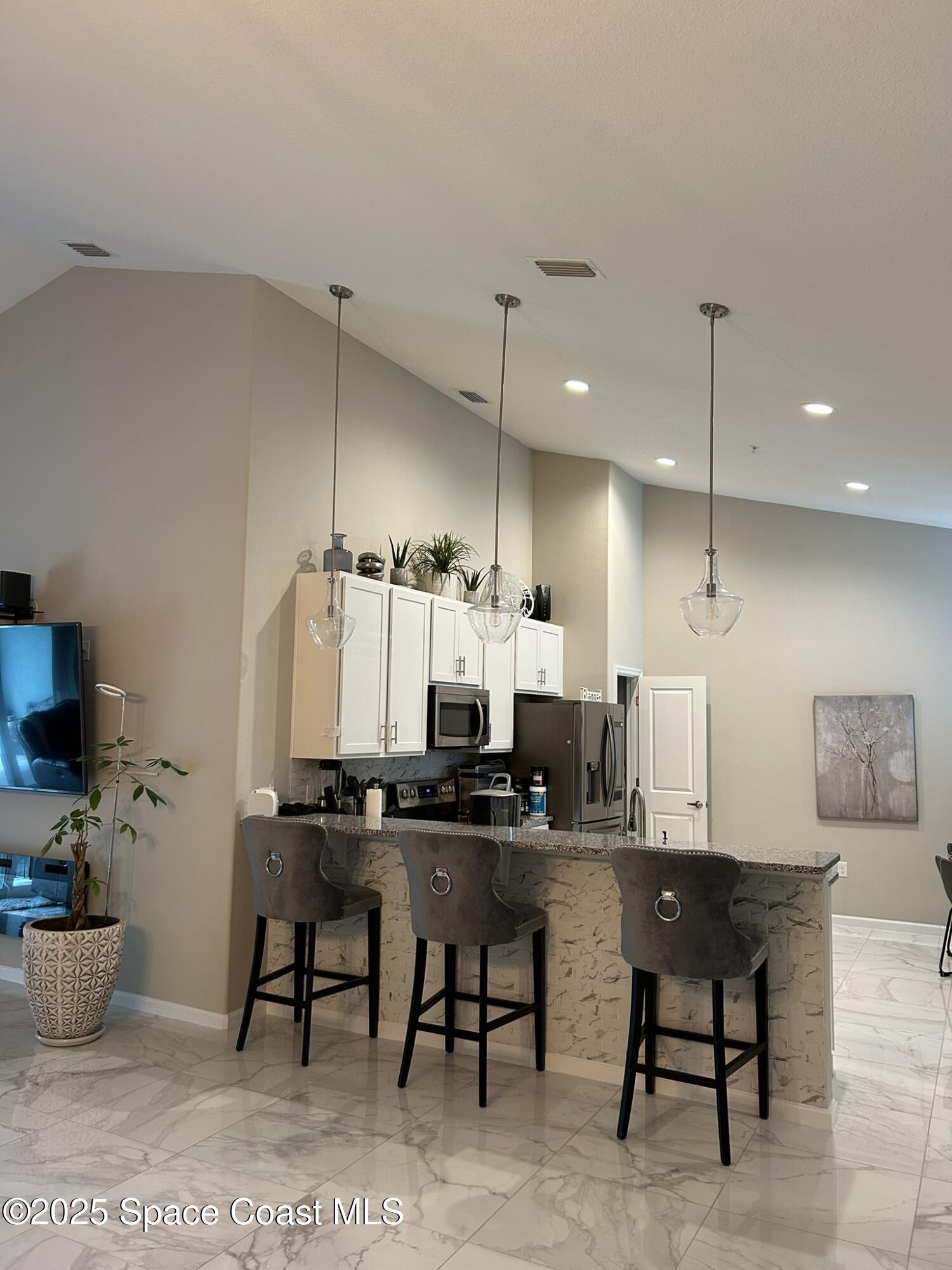 3931 Playa Del Sol Drive, Unit 203 Rockledge, FL 32955 - Photo 6 of 36 a kitchen with kitchen island a dining table chairs sink and cabinets