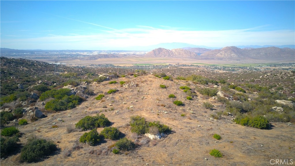 a view of a dry field with mountains in the background