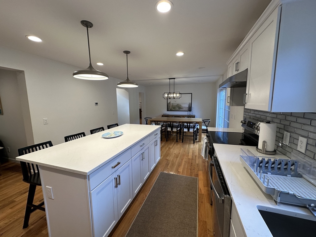 151 Tashmoo Avenue Tisbury, MA 02568 - Photo 7 of 28 a large kitchen with a stove a sink dishwasher a oven a dining table and chairs with wooden floor