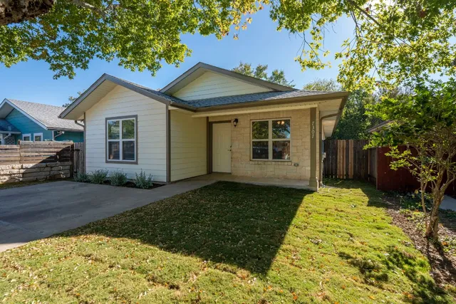 a view of a house with a small yard plants and large tree