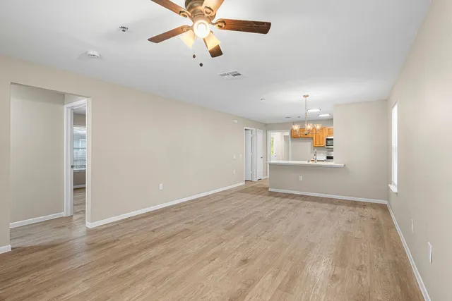 an empty room with wooden floor and fan