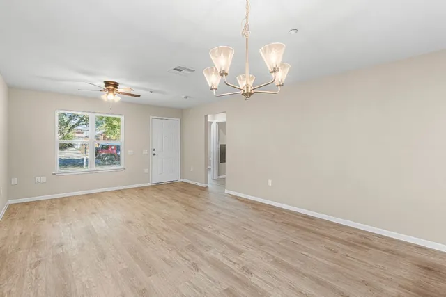 an empty room with wooden floor fan and windows