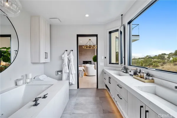 a large bathroom with a double vanity sink a large mirror and a bathtub next to a window