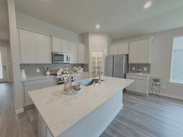 a kitchen with kitchen island a stove a sink a refrigerator and cabinets