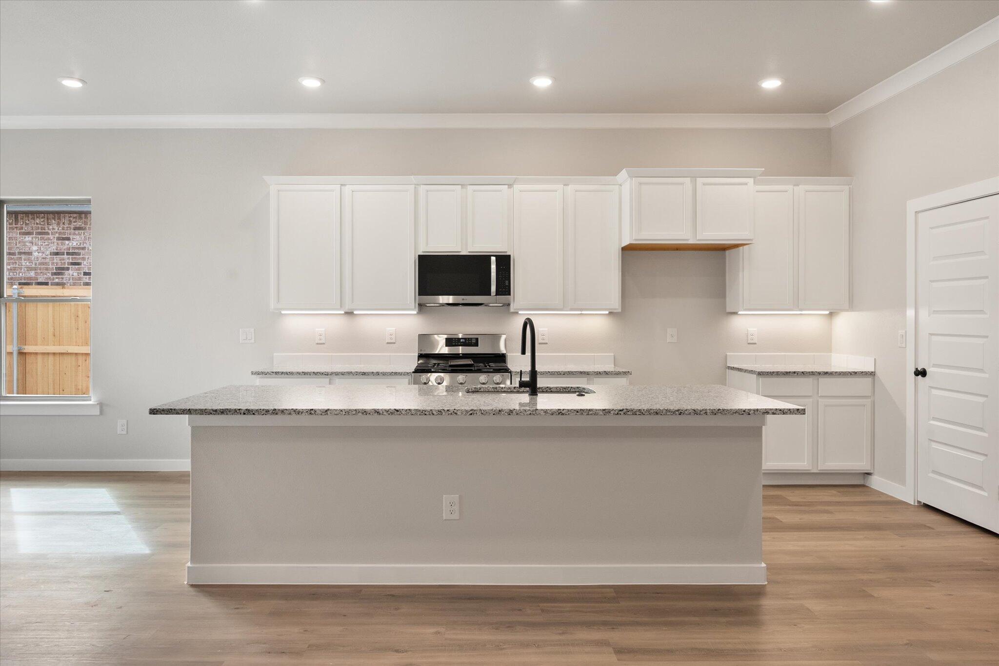 6827 54th Street Lubbock, TX 79407 - Photo 8 of 23 a kitchen with kitchen island granite countertop a sink a counter top space and cabinets