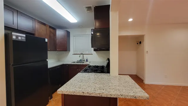 a kitchen with granite countertop a refrigerator and a sink