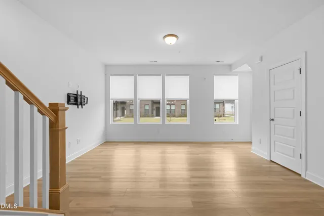 a view of an empty room with a window and wooden floor