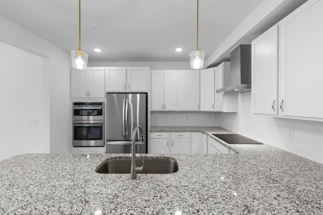 a kitchen with stainless steel appliances granite countertop a sink a stove and a refrigerator