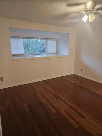 a view of empty room with wooden floor and fan