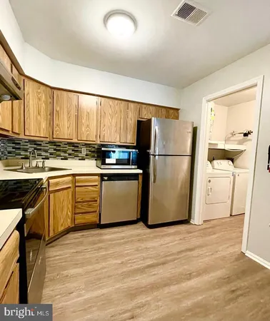 a kitchen with a refrigerator a stove top oven a sink and dishwasher with wooden floor