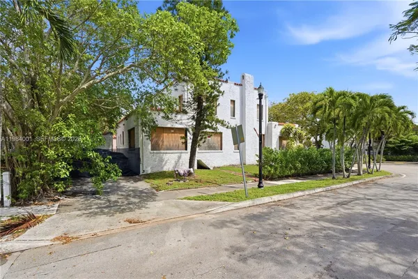 a view of a house with palm trees and a small yard