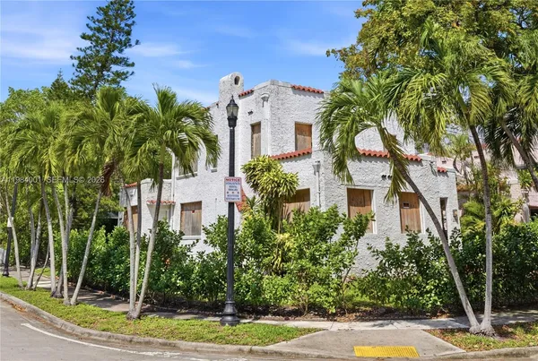 a view of a white house with a yard and potted plants