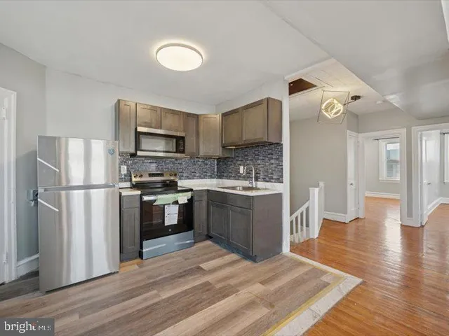 a kitchen with a refrigerator cabinets and wooden floor