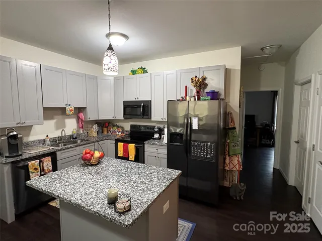 a kitchen with stainless steel appliances granite countertop a refrigerator a stove top oven a sink dishwasher and microwave with wooden floor