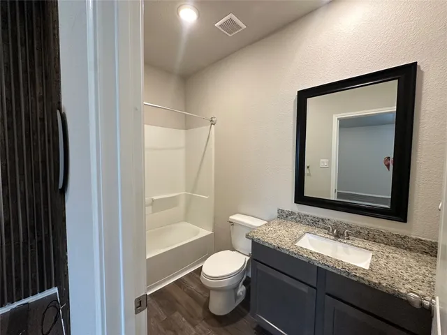 a bathroom with a granite countertop toilet sink and mirror