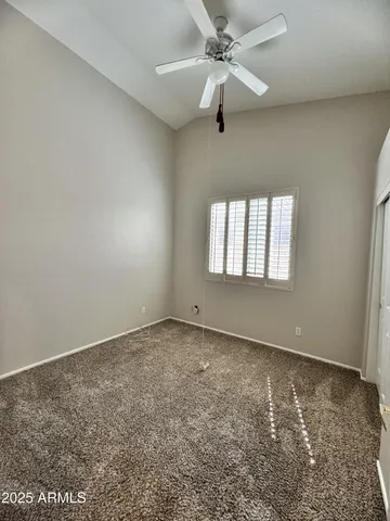 an empty room with chandelier fan and windows