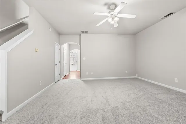 an empty room with chandelier fan and windows