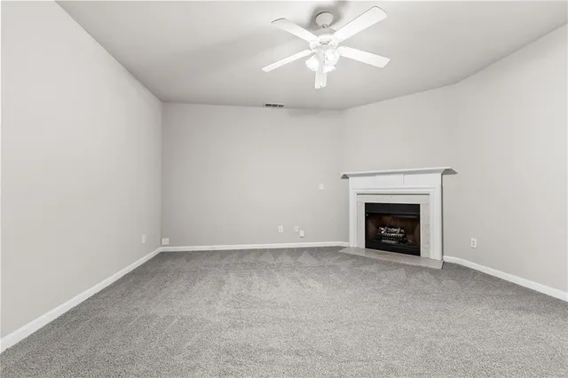 an empty room with a fireplace and a ceiling fan