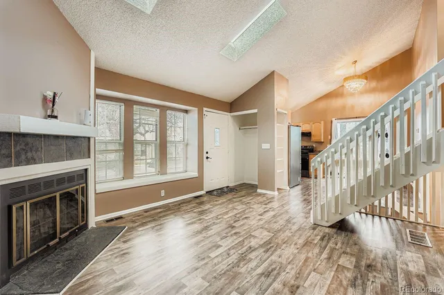 a view of an empty room with wooden floor fireplace and a window