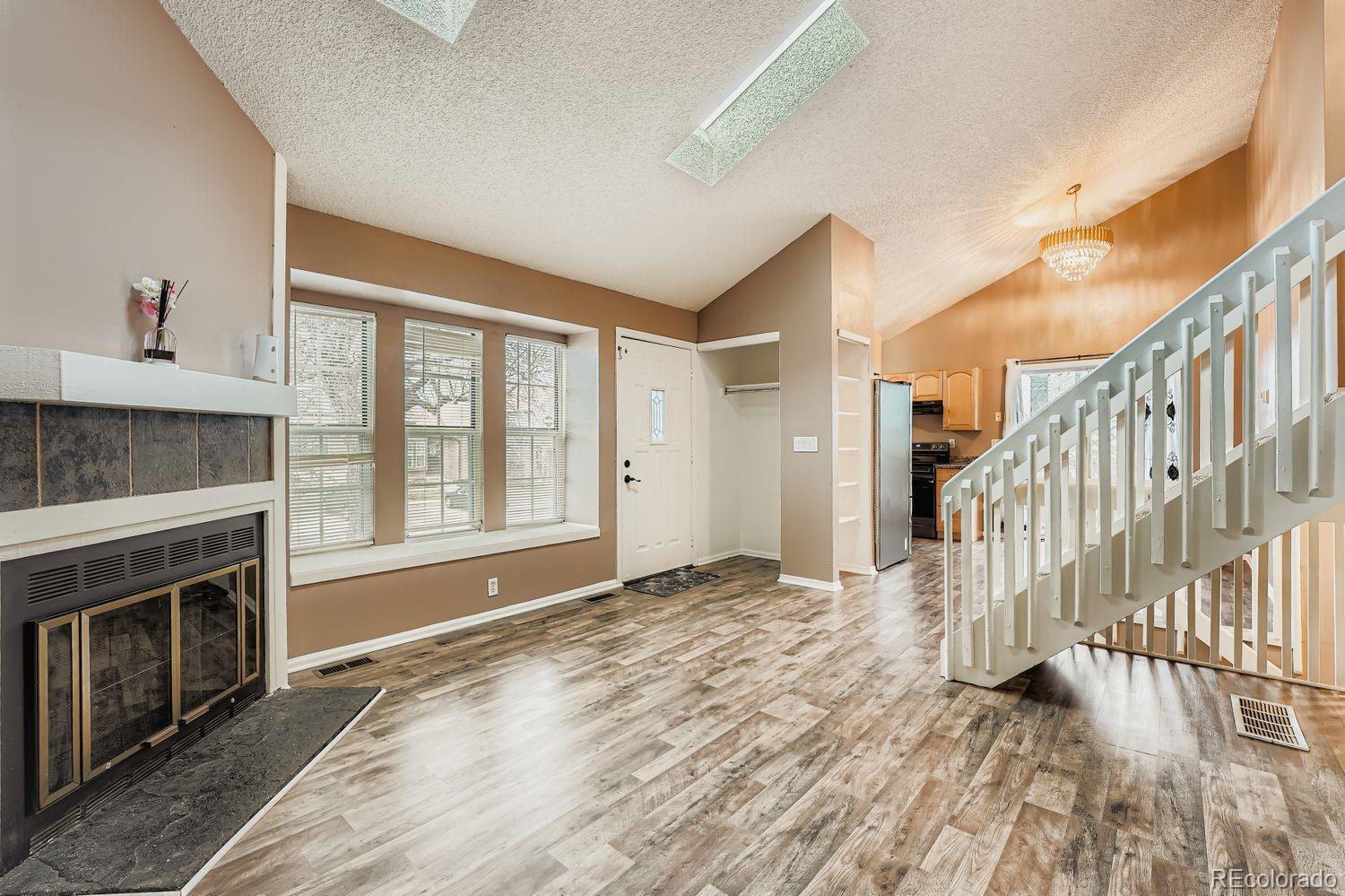a view of an empty room with wooden floor fireplace and a window